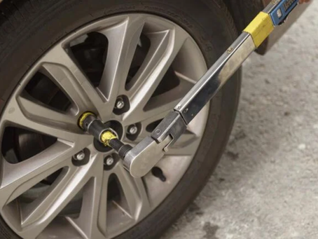 Person using a torque wrench to tighten a bolt on a vehicle component.