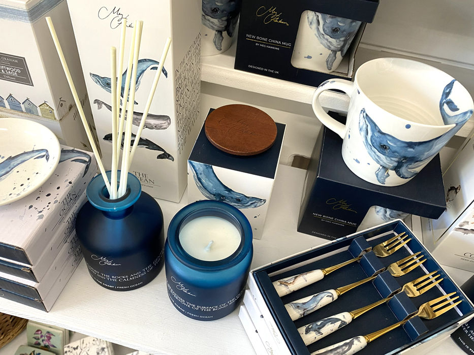 white china mug, gold dessert forks with white china handles and reed diffuser and candle boxes all printed with humpback whale watercolour painting and Meg Hawkins Art branding