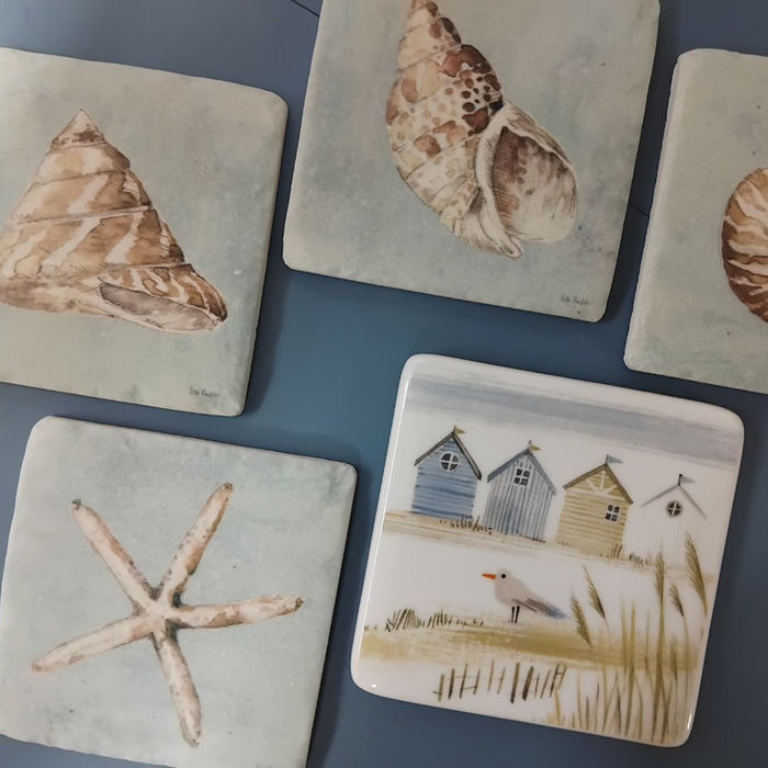Selection of coasters with seashells and beach huts.