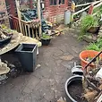 paved garden path with planters on either side leading to a wooden shed