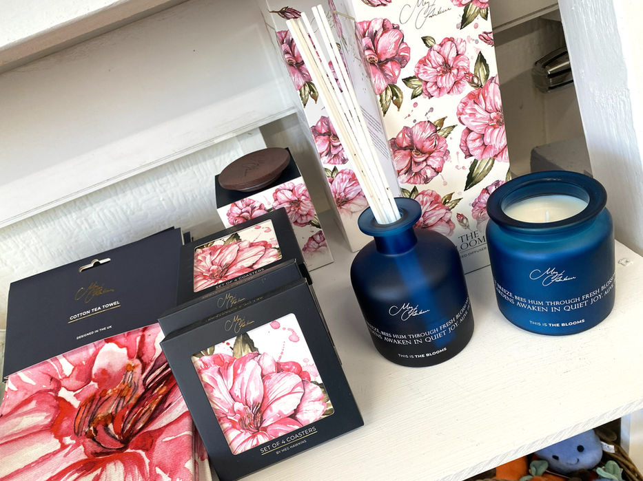 teatowel, coasters and reed diffuser box all printed with pink peony watercolour painting along with blue glass reed diffuser and candle all with Meg Hawkins Art branding