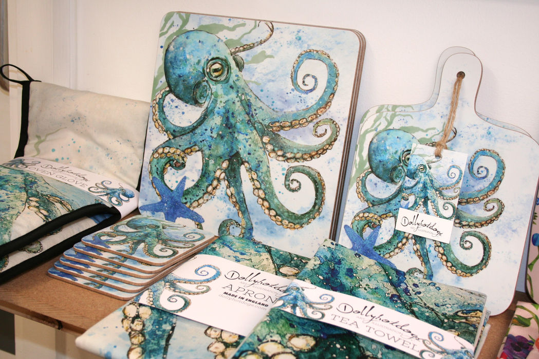 white placemants, cutting board, coasters and teatowel printed with realistic blue/green octopus and blue starfish with Dollyhotdogs branding