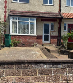 front garden cleared of shrubs and weeds, showing paved patio and stone steps to front door