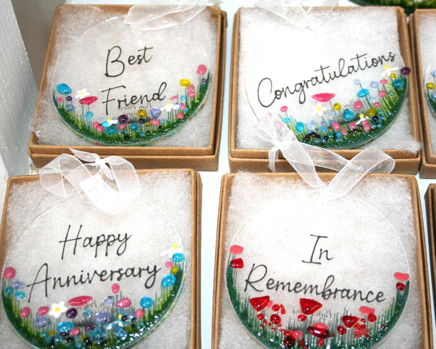 four boxed round glass hanging decorations. three have multi coloured flowers al the bottom and text above, one reads 'Best Friend' another 'Congratulations' and the third 'Happy Anniversary'. the fourth has red poppies at the bottom and the words 'In Remembrance'