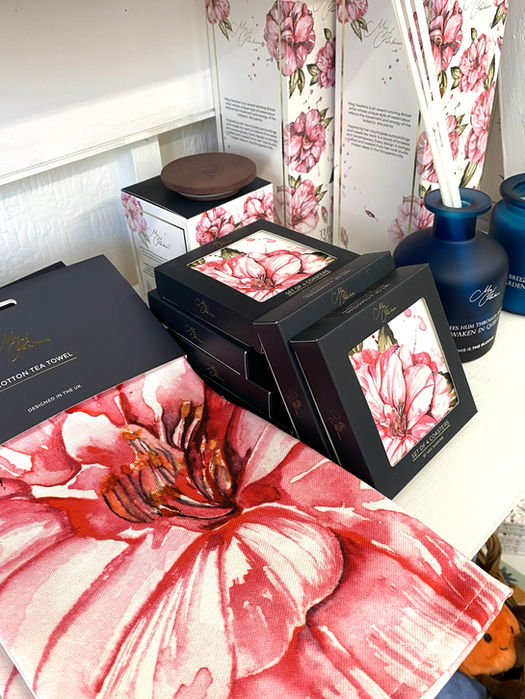 teatowel, coasters and reed diffuser box all printed with pink peony watercolour painting along with blue glass reed diffuser and candle all with Meg Hawkins Art branding