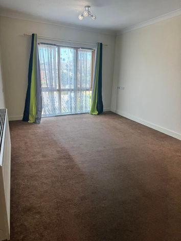 cleared living space with brown carpet and green and black curtains