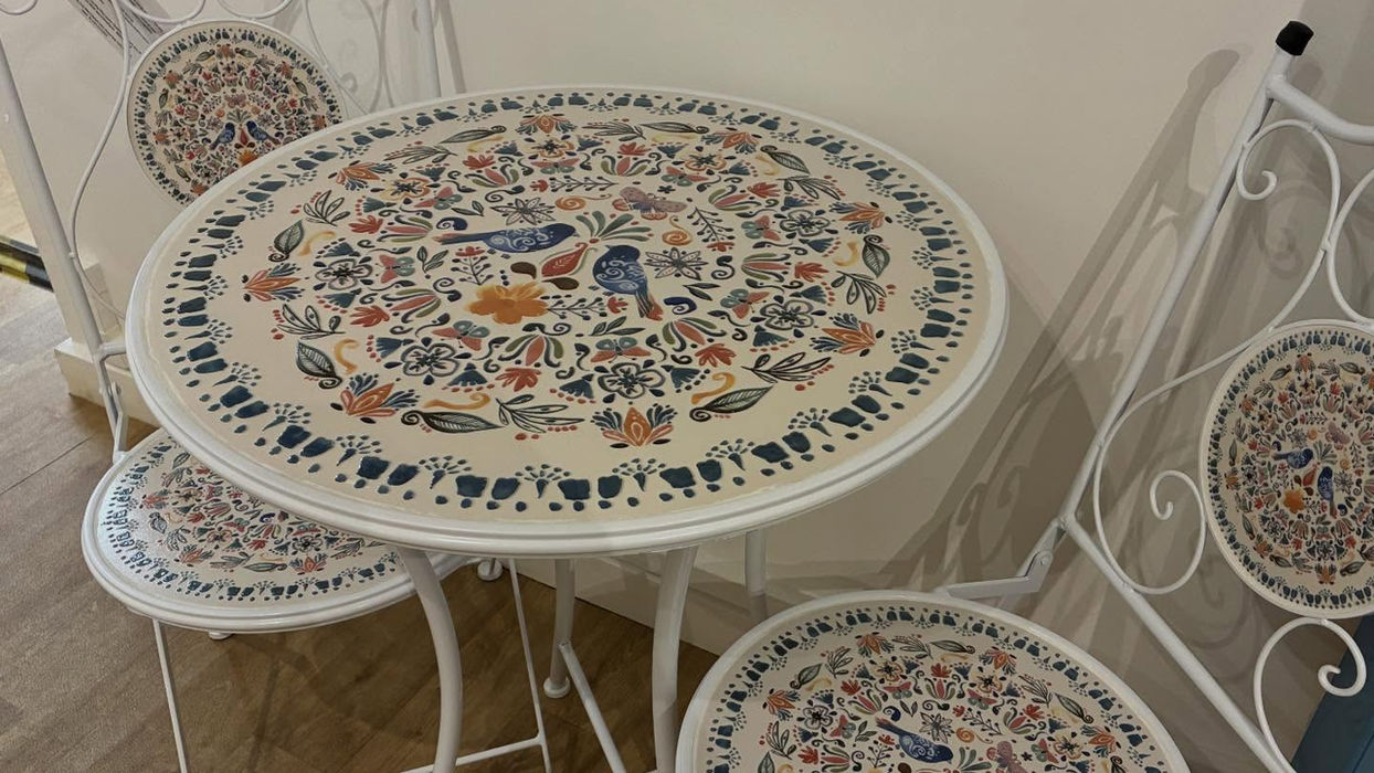 white metal bistro set decorated with blue and orange bird and flower motif