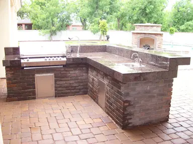 outdoor kitchen with bbq grill, sink and outdoor firepit.