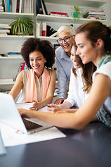 a group of people looking at a laptop and smiling