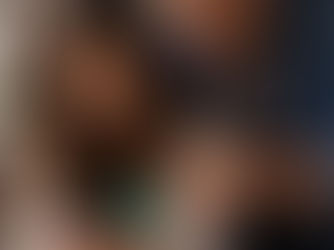 Donna seduta al tavolo con espressione preoccupata mentre il partner controlla il suo telefono e la pressa, scena che rappresenta violenza psicologica e controllo coercitivo in una relazione.