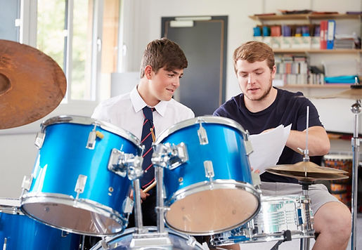 male-pupil-with-teacher-playing-drums-in-music-lesson.jpg