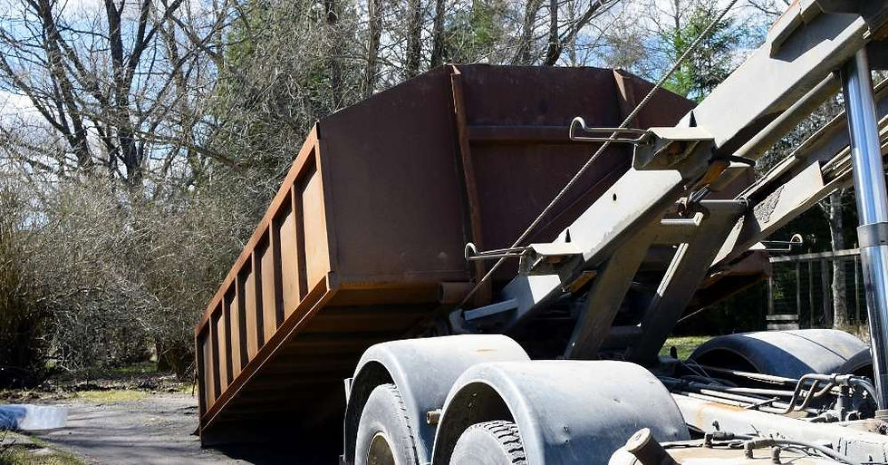 A rust-colored dumpster is being lifted onto a truck.