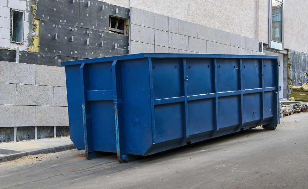 Large blue construction dumpster on a street beside a building facade under renovation.