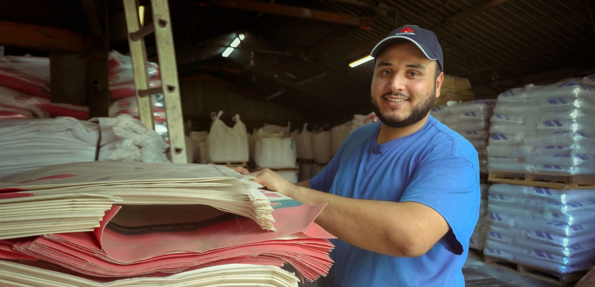 Travailleur étranger souriant manipulant des sacs dans un entrepôt agroalimentaire au Québec avec l’appui d’ARIMÉ Canada