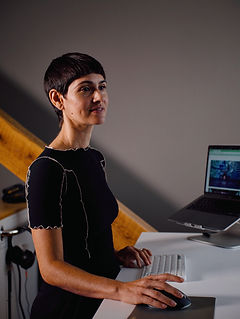 Lisa Jamhoury standing looking at her desk and computer monitors