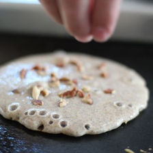 Adding toppings to a pancake cooking on the griddle