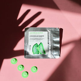 Photo des cosmétiques Romy sur un fond rose, avec l'ombre d'une main