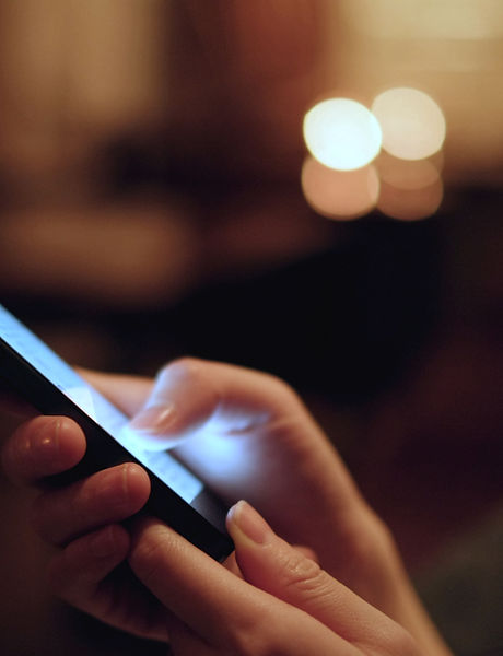 Eine Person, die ein Smartphone bedient. Dunkler Hintergrund, das Display leuchtet.