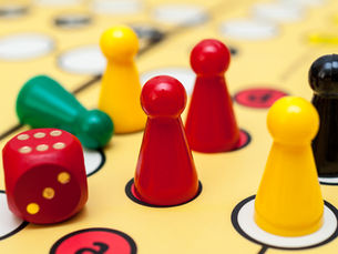 Figuren und ein Würfel im Gesellschaftsspiel Mensch ärgere Dich nicht
