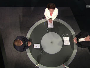 3 Personen sitzen an einem runden Tisch