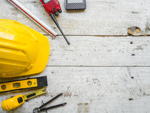 Ein gelber Arbeitsschutzhelm mit verschiedenen Werkzeugen eines Bauleiters