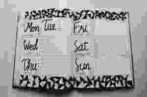 white and black weekly planner on gray surface