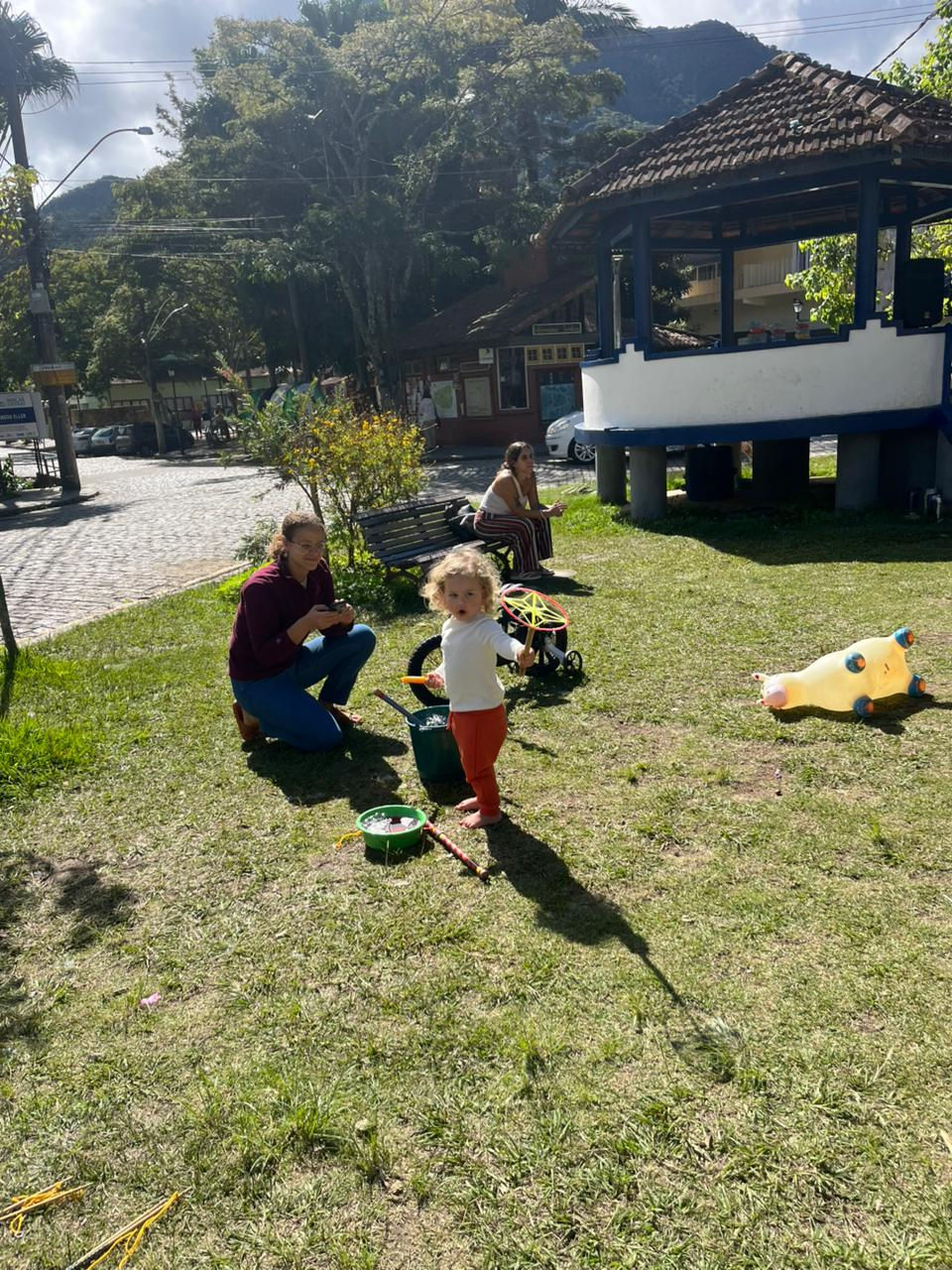 Criança em pé e adulto no gramado durante a Festa das Crianças.