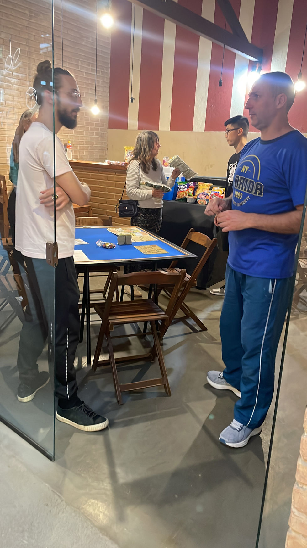 Adultos reunidos ao redor de uma mesa com toalha azul.