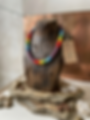 Colar africano de miçangas colorido em busto de madeira.