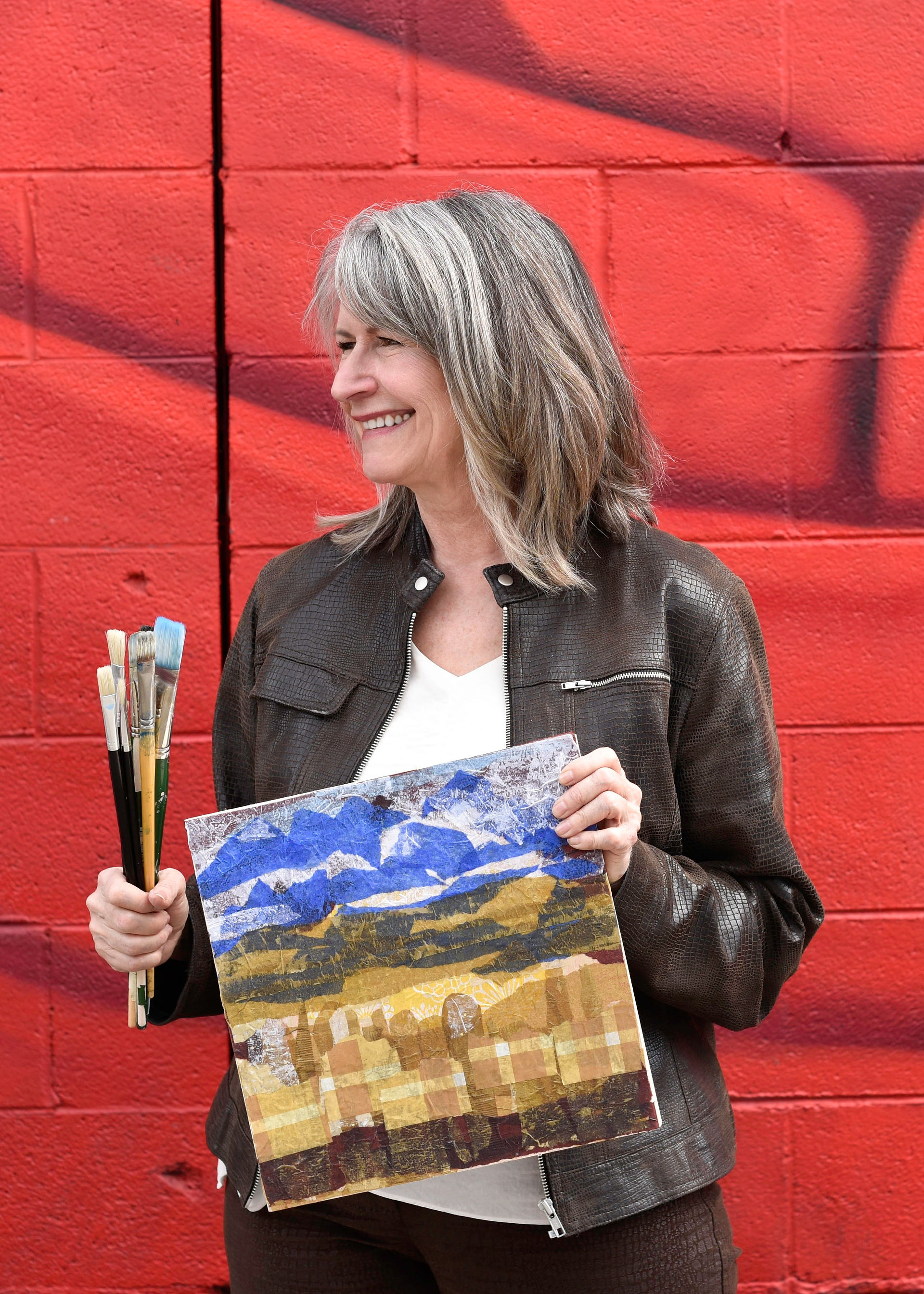 Margaret posed hosting a collage and paintbrushes.