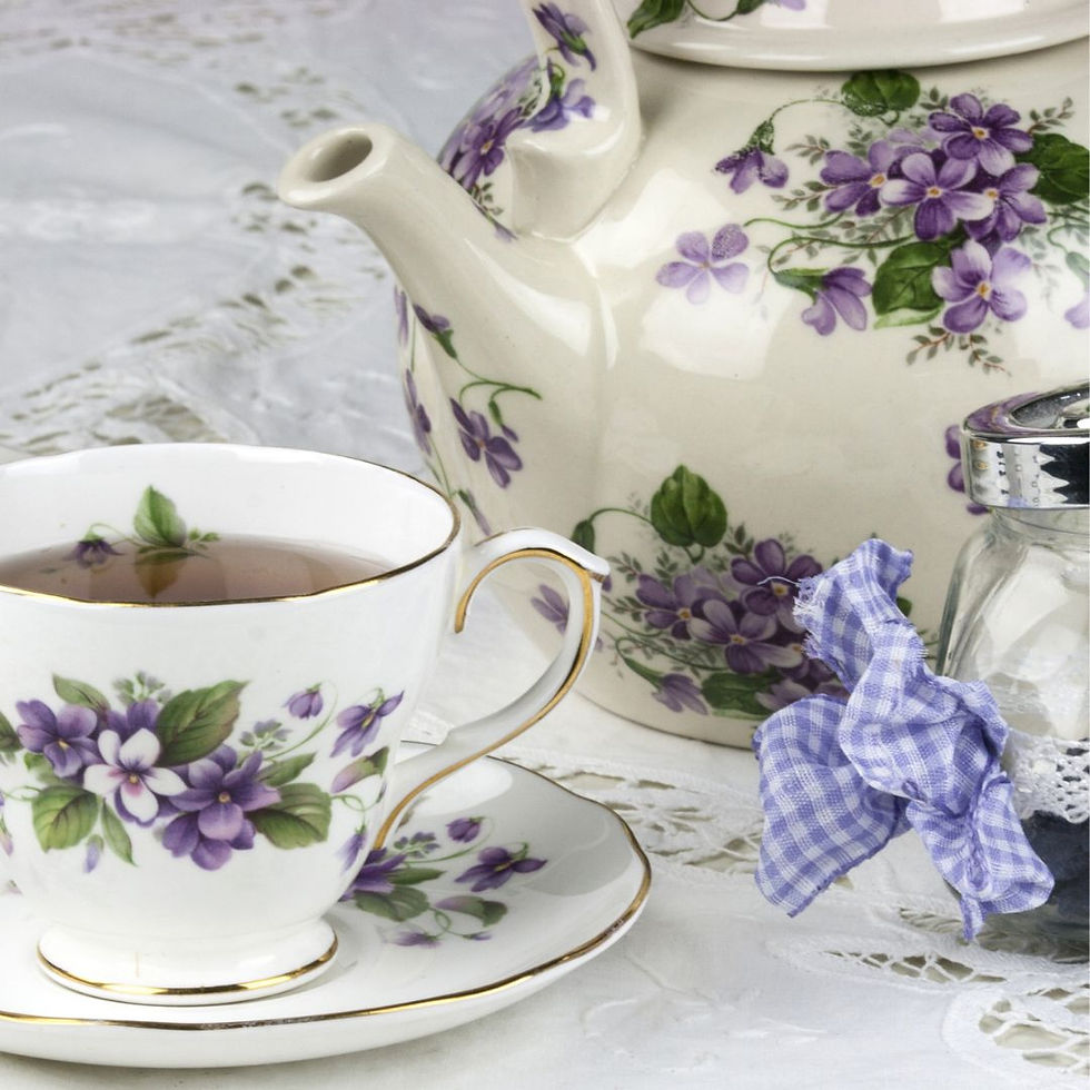 A decorative floral teapot with matching cup and saucer - flowers are lilac.