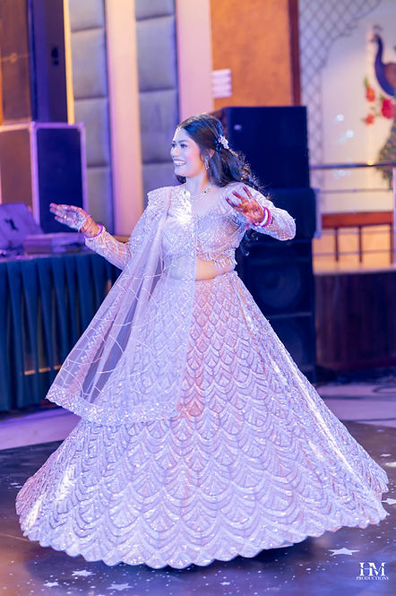 Bride dancing in a lavender lehenga on an illuminated wedding stage