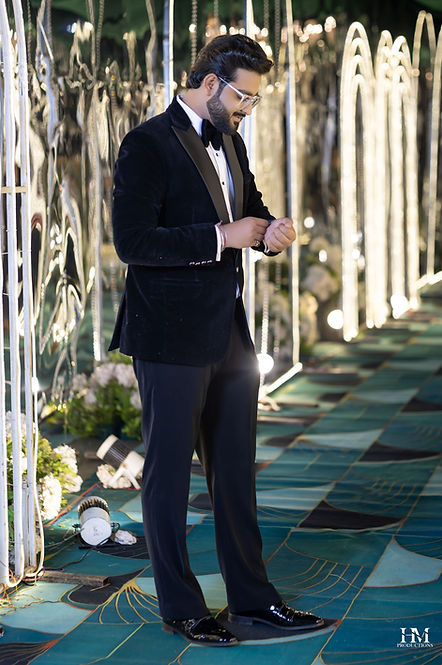 Men in a black tuxedo posing at a wedding reception