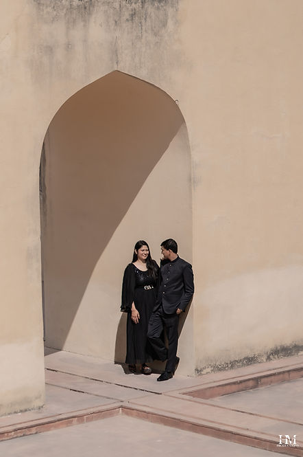 Editorial couple portrait in black outfits against a sandstone arch - Jantar Mantar, Jaipur