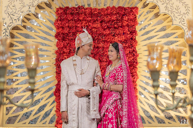 Bride and groom sharing a candid moment beneath the floral wedding backdrop