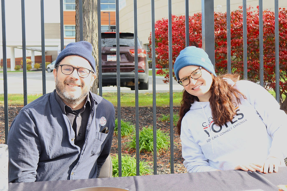 A white man and woman smile for the camera while they sit at a table outside the Cuyahoga County Board of Elections