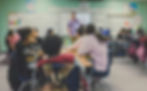 A young, male teacher instructs a diverse classroom of middle school aged children