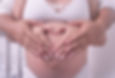 mulher grĂĄvida com as mĂŁos na barriga junto com o pai