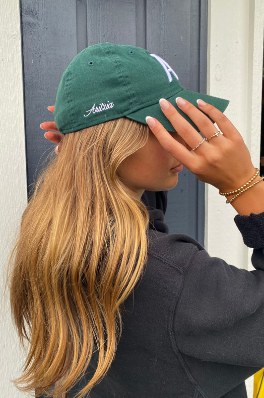 Business owner smiling in a green cap, representing Design by KJ's client-first approach