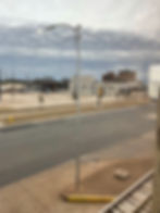 View from the window of apartment looking south towards United Regional Hospital. There is a busy street separating the building from a modern mostly empty parking lot and a street light in front of the window.