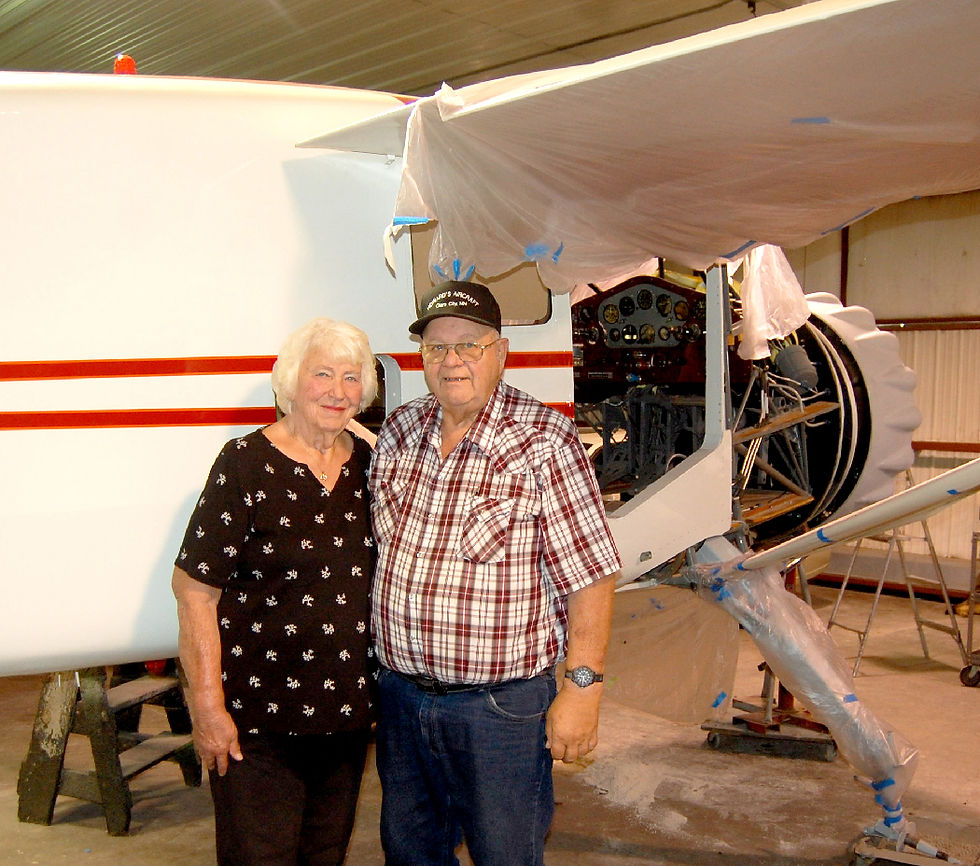 Joyce and Howard Kron stand outside the 1935 Stinson Reliant plane they are currently rebuilding. The couple has been married for 60 years and have worked on planes together for most of those years. Photo by Scott Thoma