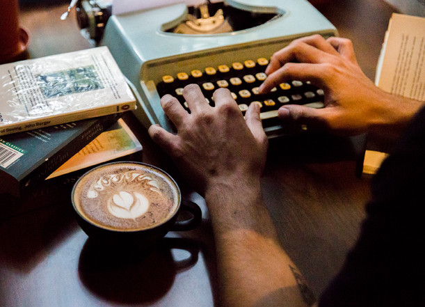 Capuccino shot with a book and a typewriter and hands at work