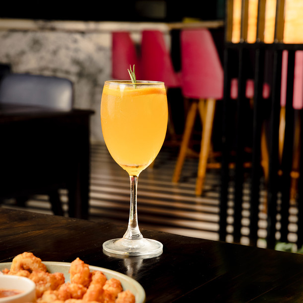 An orange spritzer shot with some calamari with a backdrop of the interiors of the place