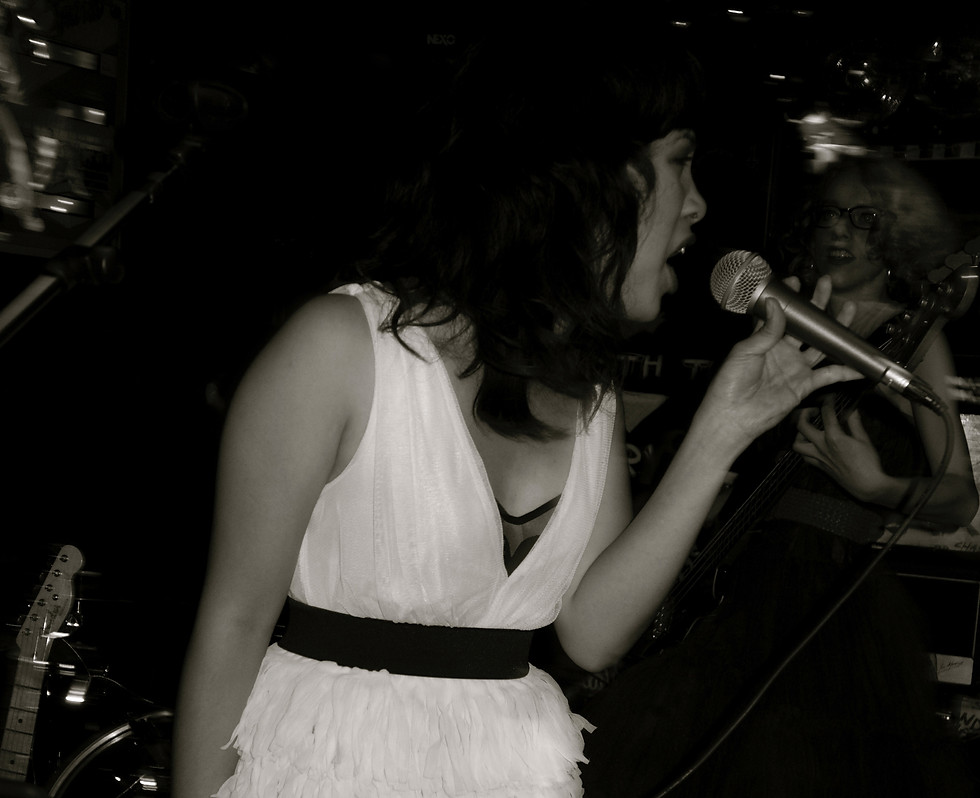black and white image of singer with profile view singing into handheld microphone at a live show