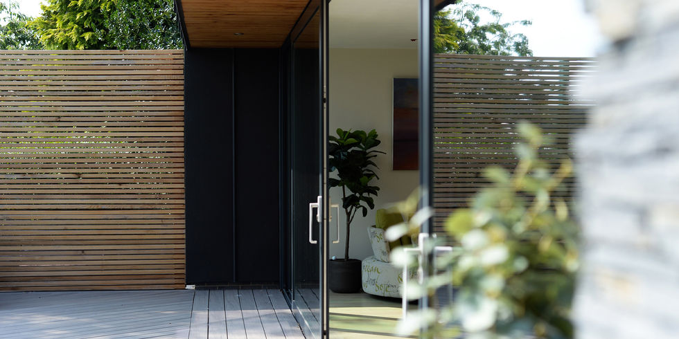 Modern entrance with black door and a wooden fence; exterior design and architecture.