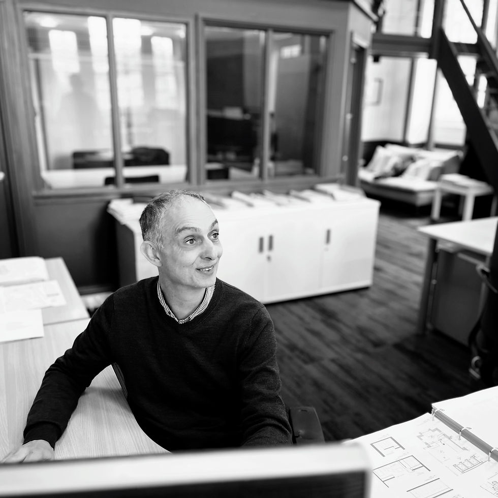 Man at desk, looking away, in a modern office. JWA Architects