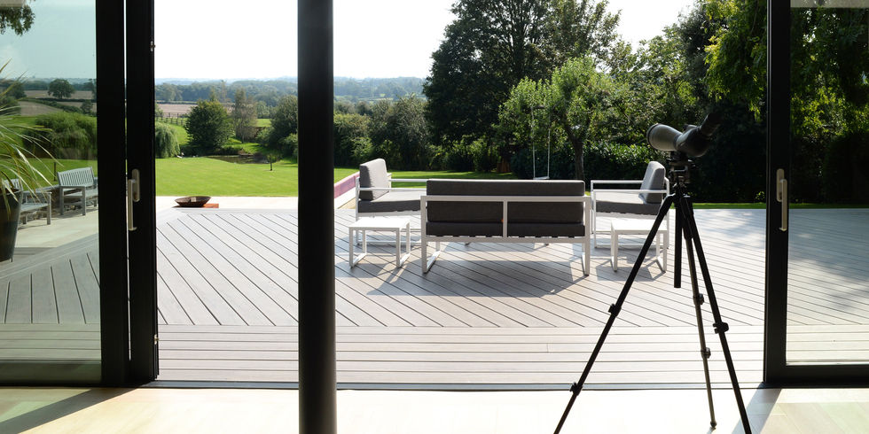 Patio scene with outdoor furniture, trees, and expansive green grass view.