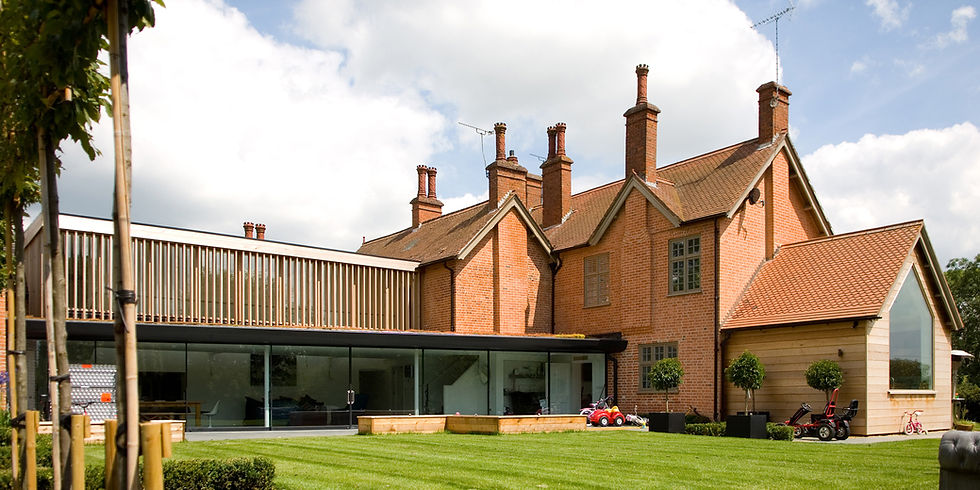 Large brick home with glass windows and a green lawn, residential design solutions.