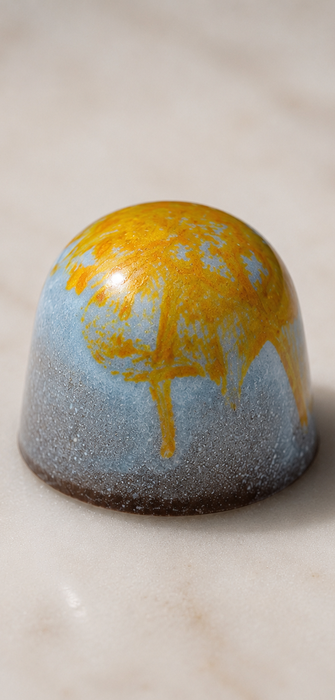 Domed chocolate bonbon with blue and gold drizzle