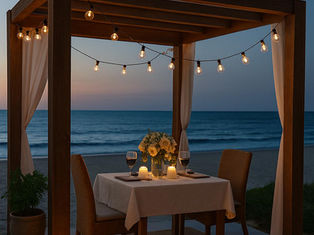 Cena romántica al atardecer bajo una pérgola de madera junto al mar, decorada con luces cálidas, cortinas y una mesa elegante, representando el estilo exclusivo de Pergomalaga.
